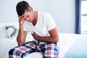 young-man-sitting-with-stomach-pain-on-bed